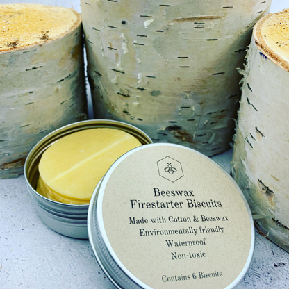A tin of beeswax firestarter biscuits with birch tree stumps in the background. made with Cotton & Beeswax, environmentally friendly, waterproof and non-toxic. Tin contains 6 biscuits.