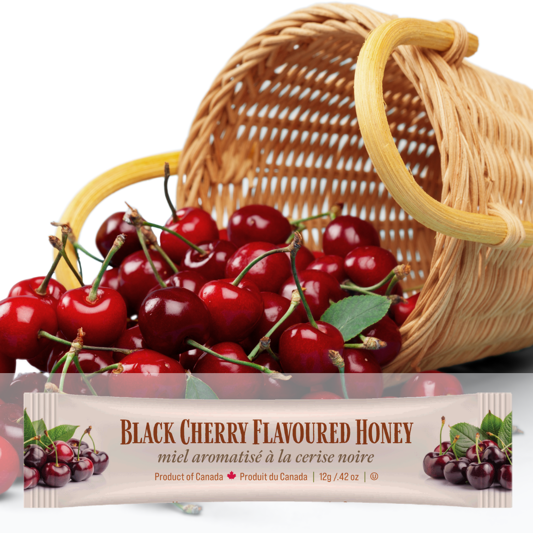 A mini squeeze pack of Tu-Bees Black cherry flavoured honey with a basket of cherries on a white background
