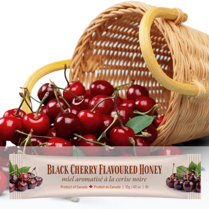 A mini squeeze pack of Tu-Bees Black cherry flavoured honey with a basket of cherries on a white background