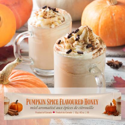 Two pumpkin spice lattes with whipped cream and chocolate shavings, surrounded by pumpkins and autumn leaves. A mini squeeze pack of Tu-Bees Pumpkin Spice Flavoured Honey at the bottom.