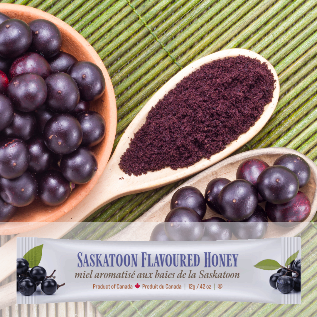 A bowl of saskatoon berries, ground Saskatoon berry powder in a spoon, and a package of saskatoon berry flavoured honey on a green mat.